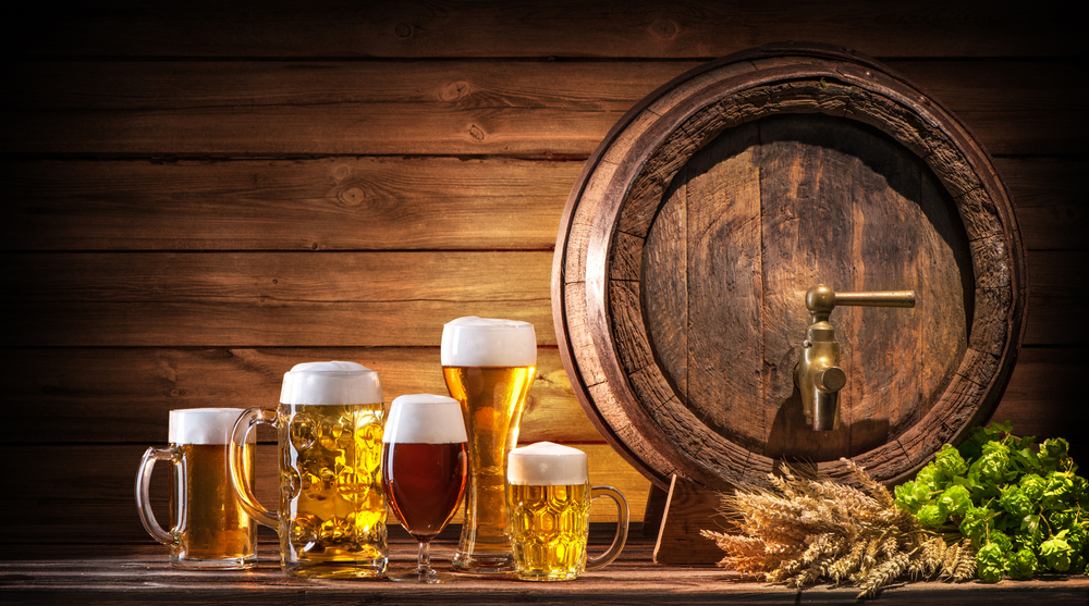 木のテーブルの上に、オクトバーフェストのビール樽と小麦とホップのビールグラスが置かれている