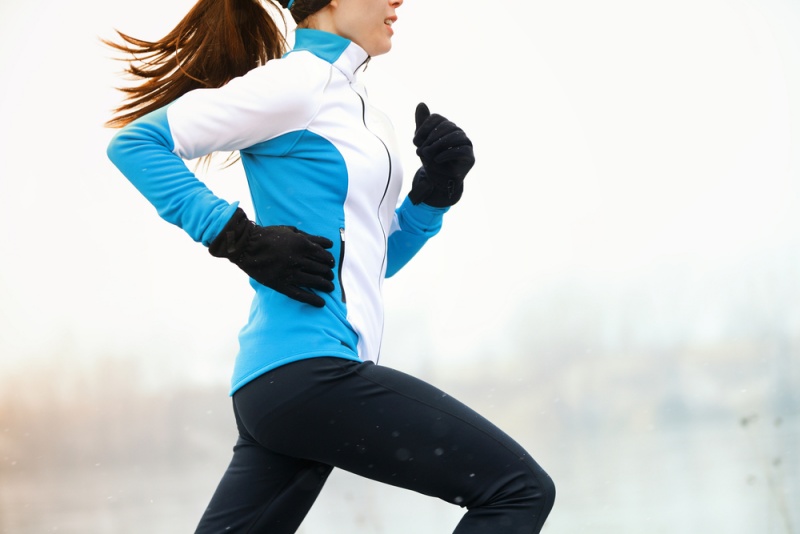 寒い雪の中、外で冬の訓練をしている間に走る運動選手の女性。速度と動きを示す接写。