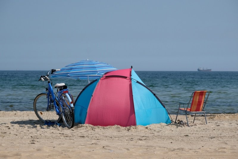 海辺にはテントと日傘、その横には自転車があります。