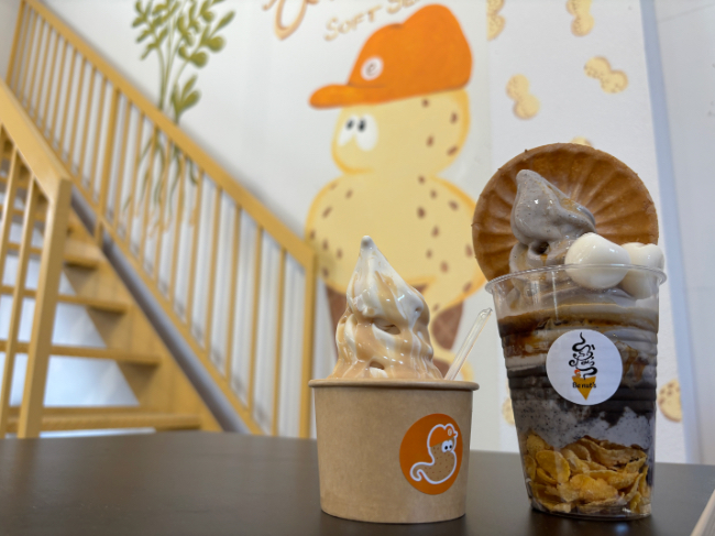 ピーナッツモチーフのアートをバックにした店員さんおすすめ商品2点