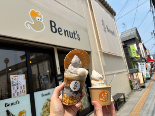 店鋪外でパフェとソフトクリームを手で持っている