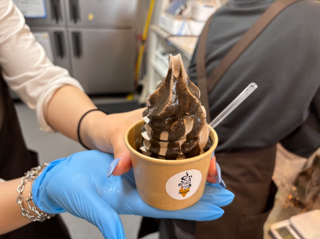 店員さんが濃黒ごまソフトクリームを手に持っている