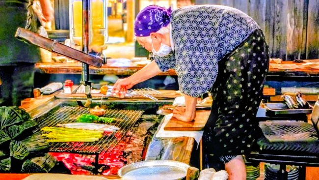 立ってしいたけに出汁をかける2代目90歳の女将